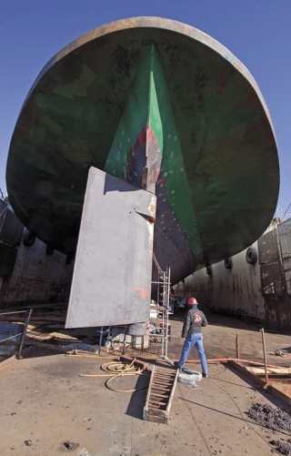 A worker walks past the rudder of the ferry Cathlamet as it sits in drydock at Anacortes for routine maintenance and inspection. One of the mainstays of the Clinton-Mukilteo route