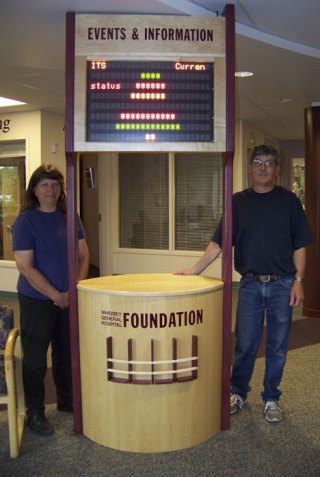 Sandy and Gary Leake of Gary A. Leake Woodworking stand next to the new kiosk at Whidbey General Hospital that was created by Gary Leake.