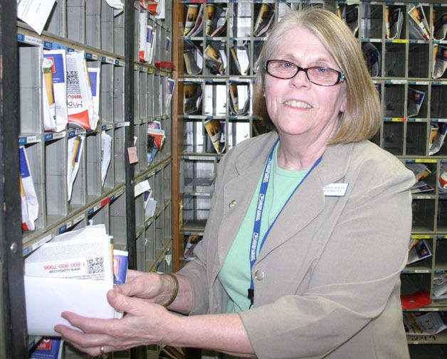 Carol Avery stuffs some post office boxes at the Freeland post. She will retire at the end of July