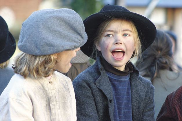 Margeaux Scholz and Juliana Larson-Wickman belt out a tune from “Oliver! The Musical” as a float filled with youngsters from the production at Whidbey Island Center for the Arts makes its way down First Street on Saturday for the Langley Holiday Parade.