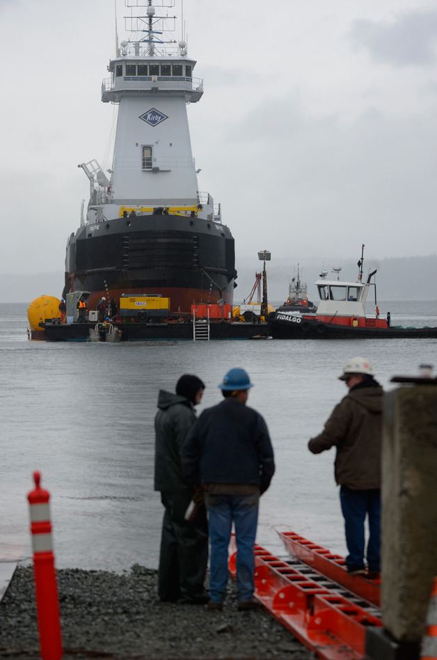 Nichols Brothers Boat Builders employees watch from the shore as a new tug boat built in Freeland attempts to leave Holmes Harbor on Feb. 12.