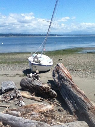 Clinton resident Jordan Dow waits on the rocks of Hat Island for help to arrive after he encountered rough waters with his sail boat.