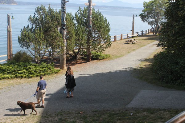Edmonds residents Craig and Arra Priszner walk with Alex Garza of Chicago around Seawall Park on a sunny afternoon Friday in Langley. Police have found 40 used syringes in the park over the past two weeks