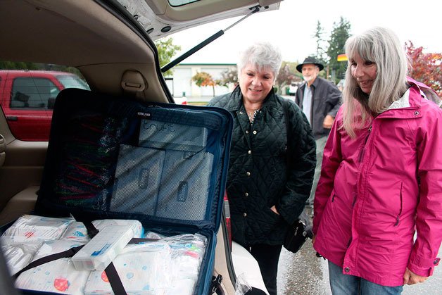 South Whidbey volunteers Marti Bauer (left) and Linda Jacobson (right) take a look at one of the 16 bags the volunteers will take on their aid trip to Haiti.