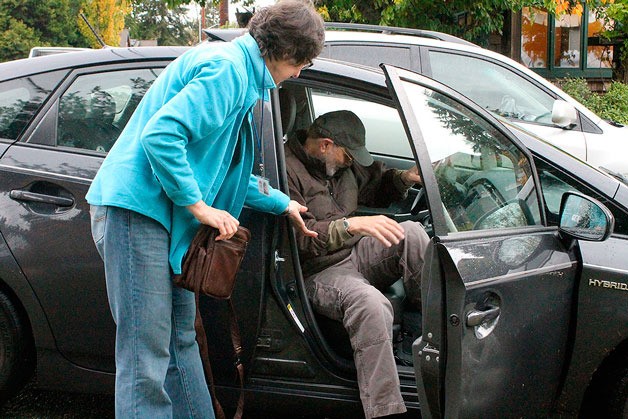 South Whidbey at Home volunteer Janice O’Mahony helps member Brad Walker out of her Toyota Prius on Thursday morning.