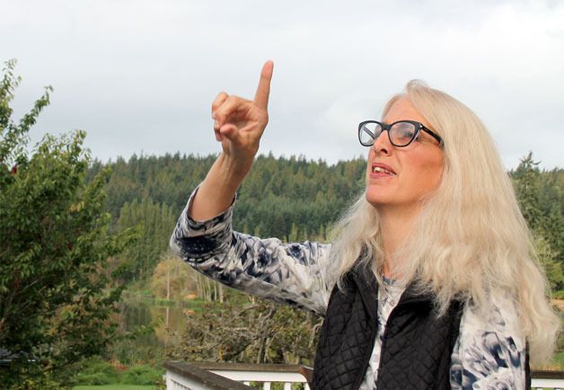Langley resident Nannette Pierson points to the sky where she saw a raptor after a trout fell onto her back lawn. The bird didn’t come back