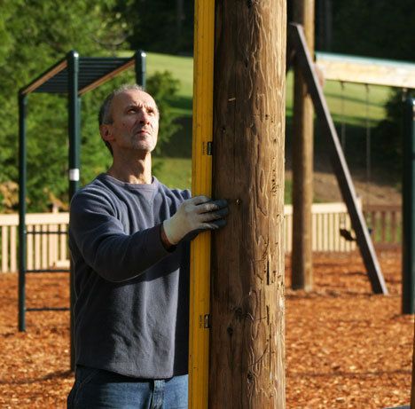 Mike Skouras measures twice before cutting once as he installs a new adult chin-up bar at Castle Park.
