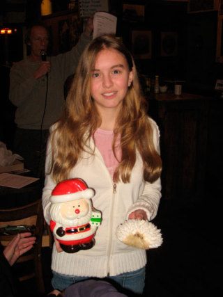 Winning poet Cassie Thomson holds the prizes bequeathed by slam emcee and Conductor of Fun Jim Freeman: a Santa Claus cookie jar filled with candy canes and a hedgehog made of sea shells.