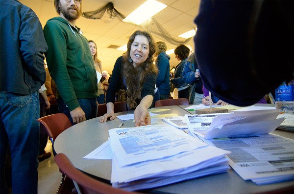 Clinton resident Natasha Burkle hands in her vote for Bernie Sanders during the Democratic caucuses at South Whidbey High School Saturday.