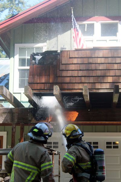 Firefighters aim to put out a smoldering fire that cost a Bayview man his balcony last week.