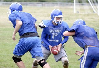 South Whidbey High School quarterback Hunter Rawls passes off to his tailback Wednesday during practice at Waterman Field.