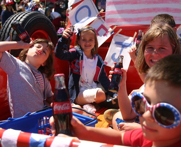 Kids enjoy a classic Coke in the flatbed of a classic truck at last year’s Maxwelton Independence Day Parade. From the left