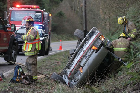 Firefighters work to pull a driver out of an overturned Ford Mustang on Monday afternoon on Sills Road.