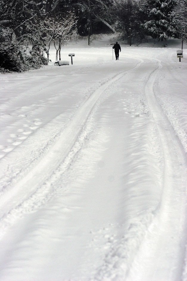 A South Whidbey resident carries a push broom while on his way to brush off his car that was left on the side of the road after he could not make it to the top of the hill on Fidalgo Drive.