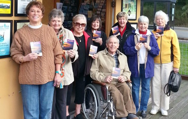 Volunteers at the Visitor Information Kiosk receive the Shop Local coupon book. From left to right are Donna Hood
