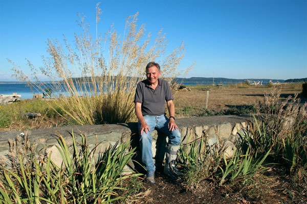 Greenbank property owner Bruce Montgomery poses for a picture on a wall at the end of Wonn Road. The wall has been a source of controversy and legal dispute for years. A judge recently denied a second request to end a lawsuit