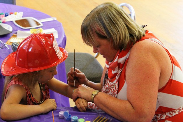 Susan Fortan decorates a girl's hand with paint during the 100-year celebration of Freeland Hall on Aug. 23.