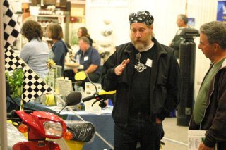 George Springer from Langley talks to a potential buyer about the benefits of a 70 miles per gallon moped Sunday at the Uniquely Whidbey Business Expo.