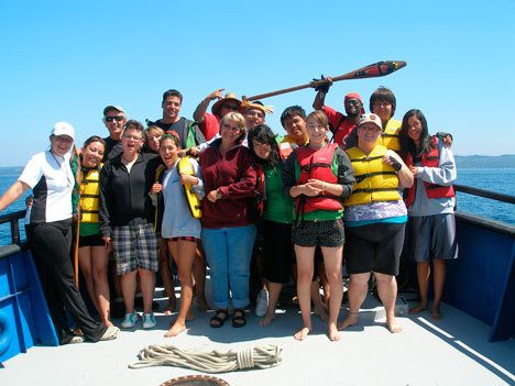 Susie Richards (center) and Chris Burt (third from left) stand on the deck of the Indigo with crew members of the Raven Dancer Canoe Family.