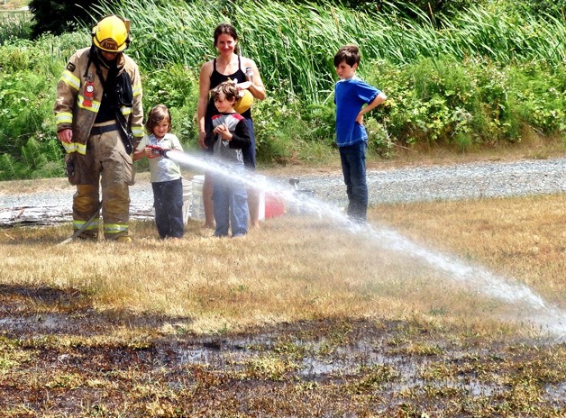 A child gets to hold the hose to douse a patch of grass that caught fire after some children used fireworks in the Sunlight Beach Road area Wednesday afternoon.