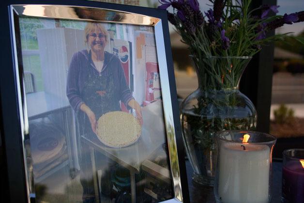 A framed photo of Kathie Baker sits next to candles and flowers left in memorial to the murdered pizzeria owner in Freeland.