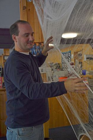 Jason Kalk sets up spider web decorations for the upcoming Clinton Halloween Community Trick or Treat event this Thursday