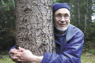 Harry Case with one of the Douglas fir trees on his 176-acre wooded property near Langley: “I’m doing what  I always wanted to do.”