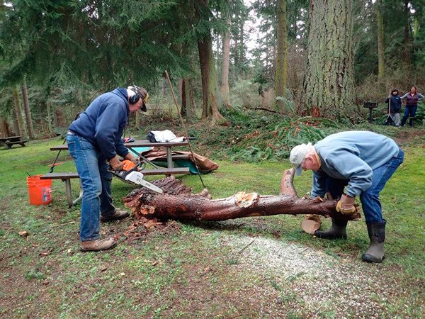 Paul Louden of Langley and Grant Heiken of Freeland remove a large limb that fell in the picnic area of South Whidbey State Park at a recent work party. Another work party is planned for this Saturday from 8:45 a.m. to noon at the park.