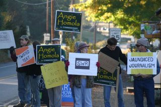 A small group of protesters gathered in Bayview Monday to complain about the coverage of county commissioner candidate Angie Homola.