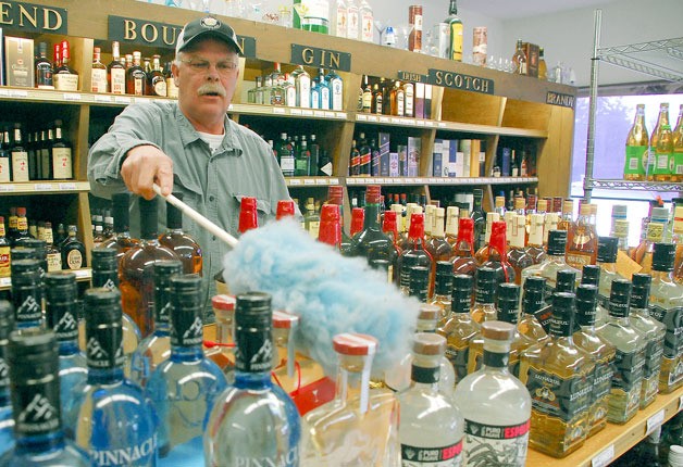 Freeland Liquor Store owner Ken Vaughan dusts bottles Thursday afternoon. He is preparing for some stiff competition if Payless Foods