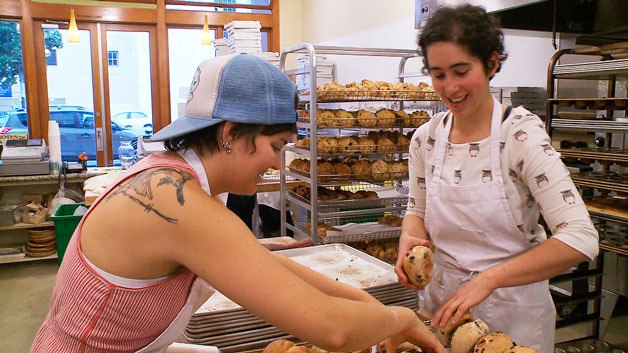 Bakers at one of the Arizmendi Bakeries near San Francisco work together to get their buns in order. The women appear in “Shift Change