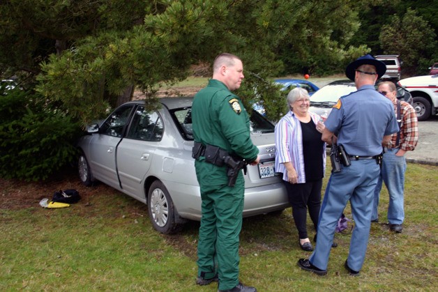 Linda Heintz of Maxwelton explains to Trooper Larsen how her car hit the tree as Deputy Crownover listens. The accident Friday occurred at about 10 a.m. Heintz was driving north on Highway 525 in front of Naomi’s gas station when she tried to slow for another vehicle.