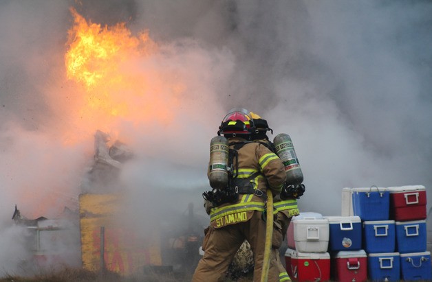 Will Piepenbrink and Mari St. Amand steady the hose as they douse a trailer engulfed in flames off Honeymoon Bay Road near Highway 525 in Freeland Friday morning.