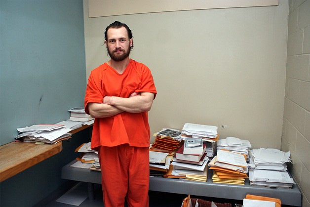 Joshua Lambert stands in his cell in Island County jail two years ago. He had a cell to himself because he was acting as his own attorney and had stacks of legal documents and books.