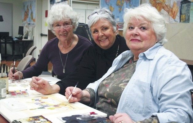 Art teacher Deon Matzen (center) offers watercolor tips to Barbara Fisler (left) and Barbara Enberg during her painting class Thursday afternoon at Skagit Valley College’s South Whidbey Center. Art classes will be dropped from the curriculum as a  cost-saving measure in the fall.
