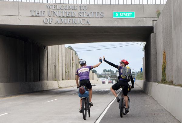 Greenbank brothers Andrew and Randall Leese cross the Washington-Canada border after riding their bikes on a round-the-world fundraising ride.