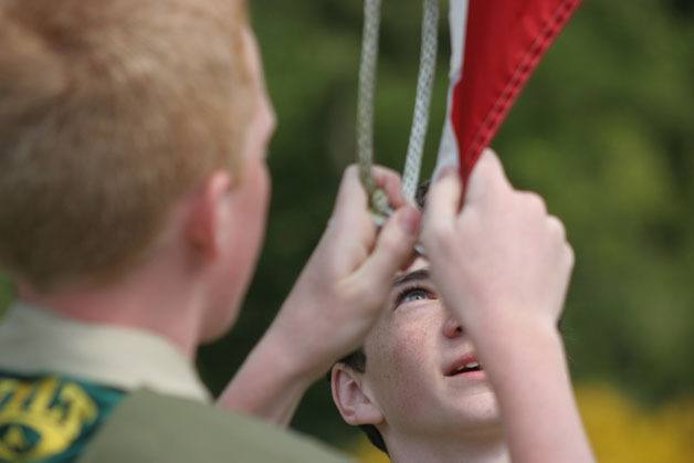 Evan Mellish of Boy Scout Troop 57 watches as fellow Scout Max Corell raises the American flag at the start of the Memorial Day service on Monday at the Clinton Cemetery.