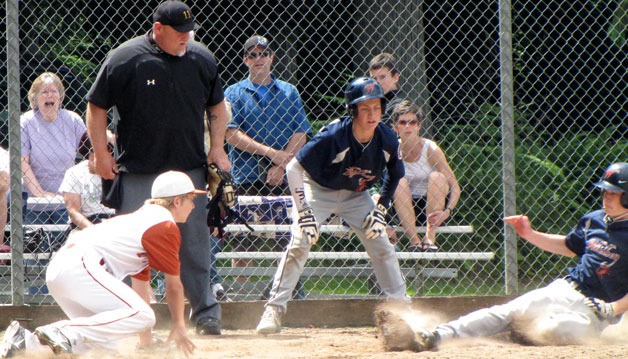 Peter Jacobs slides home safely as Charlie Patterson watches with the umpire during a game against the Mountlake Terrace Youth Athletics Association Titans.