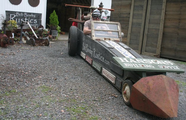 Bob Bowling shows off the racer he will enter in Saturday’s Soup Box Derby in Langley. The short course is an open soap box downhill race and features many imaginative race cars. Bowling’s is in line with his career as a rustics artist who uses old materials to fashion new sheds and garden art.