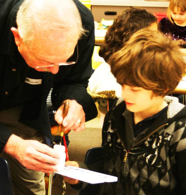 Local artist Gordon Edberg shows South Whidbey Elementary Student Liam DiLorenzo a trick of the trade during an artist-in-residence session in the classroom.