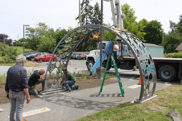The first of three steel pieces of an archway is placed into its previously constructed bolts. The archway