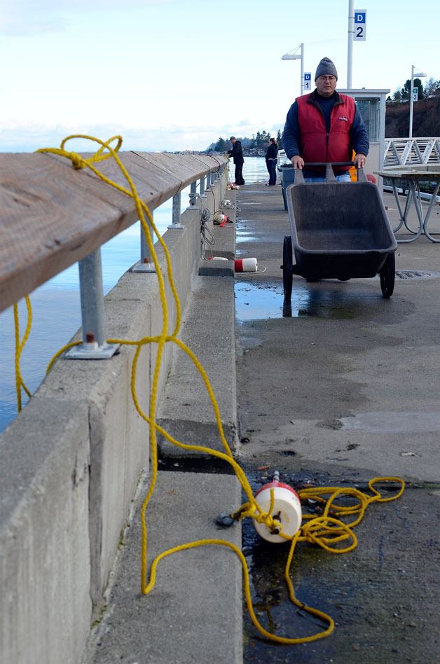 South Whidbey Harbor Harbormaster Duncan McPhee collects a dock cart used by crabbers Monday. It’s one of a slew of problems that have led to port officials proposing crabbing and fishing restrictions for the new floats outside the wooden breakwater.