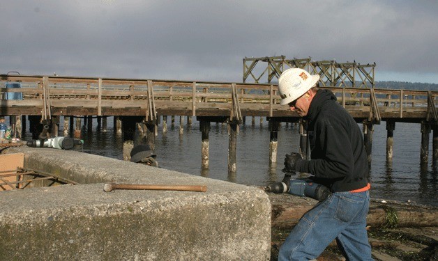 Dan Boydston drills into the concrete bulkhead to install an ADA ramp to the Langley Marina. His company