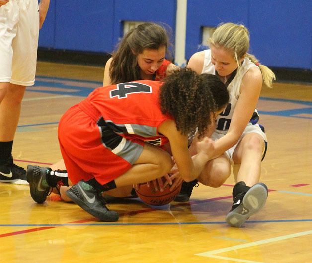 Falcon sophomore Kolby Heggenes battles for possession of a loose ball with Archbishop Murphy’s Maddie Hill and Megan Dorney. Heggenes scored nine points in the Falcons’ 63-33 loss to the Wildcats on Friday night at South Whidbey High School.