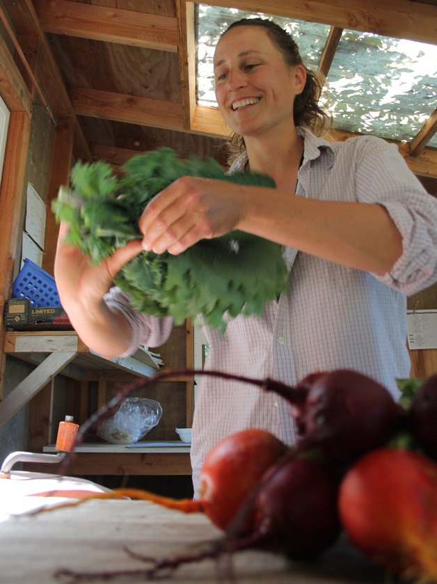 Jen White of Cedarhill Farms in Clinton bundles kale together after washing a beet bunch. Her farm is one of 21 on a brochure of Whidbey Island stands.