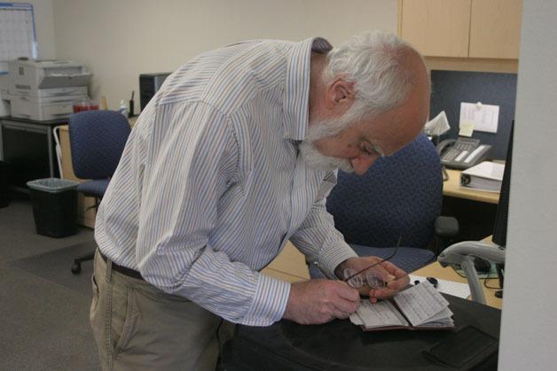 Langley City Councilman Hal Seligson writes out a check to cover his filing fee on Monday at the county elections office in Coupeville.