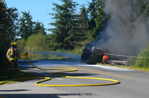 South Whidbey Fire/EMS firefighters attempt to extinguish a truck that caught fire after it hit a telephone pole on Woodard Avenue in Freeland Sunday. The accident knocked out power to hundreds or nearby residents for hours.