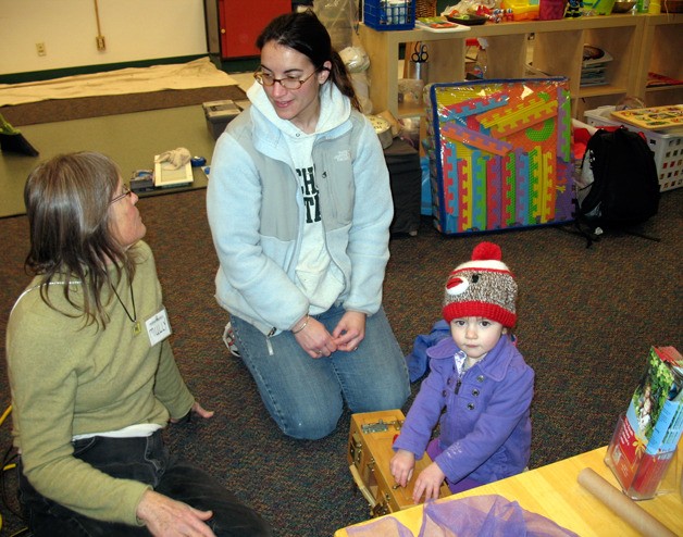 Playscape facilitator Mully Mullally engages mom Micki Neal in conversation while Neal’s 2-year-old daughter Kassidy plays nearby.