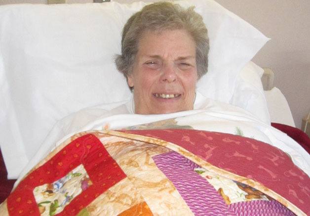Anne Chambers smiles for a picture while laying in a Coupeville hosptial bed. The well-known South Whidbey schools tutor has stage-four cancer and “laying around” is not something she’s used to.