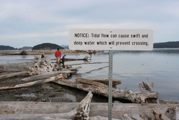 People walk on Ala Spit on North Whidbey. The park has had environmental restoration work in recent years that’s caused the spit to flood during high tides. Two fisherman were recently swept out into Puget Sound.